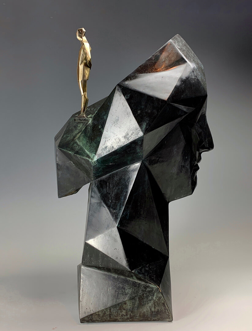 rzeźba przedstawiająca zgeometryzowany czarny profil kobiecy, na głowie stoi mała złota postać
