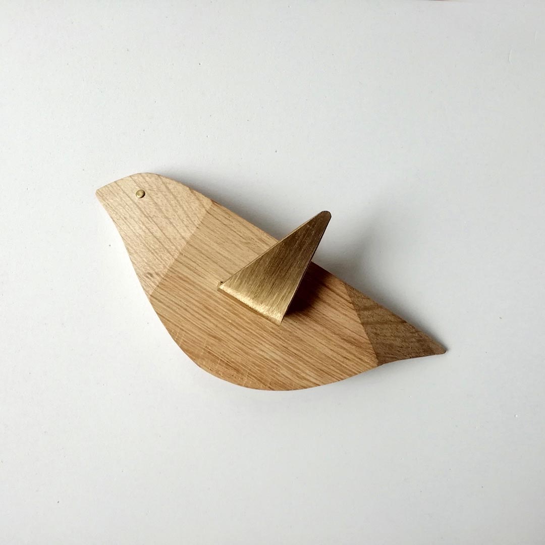 drewniany wieszak na ubrania w kształcie ptaszka. Skrzydło wykonane z mosiądzu służy jako haczyk